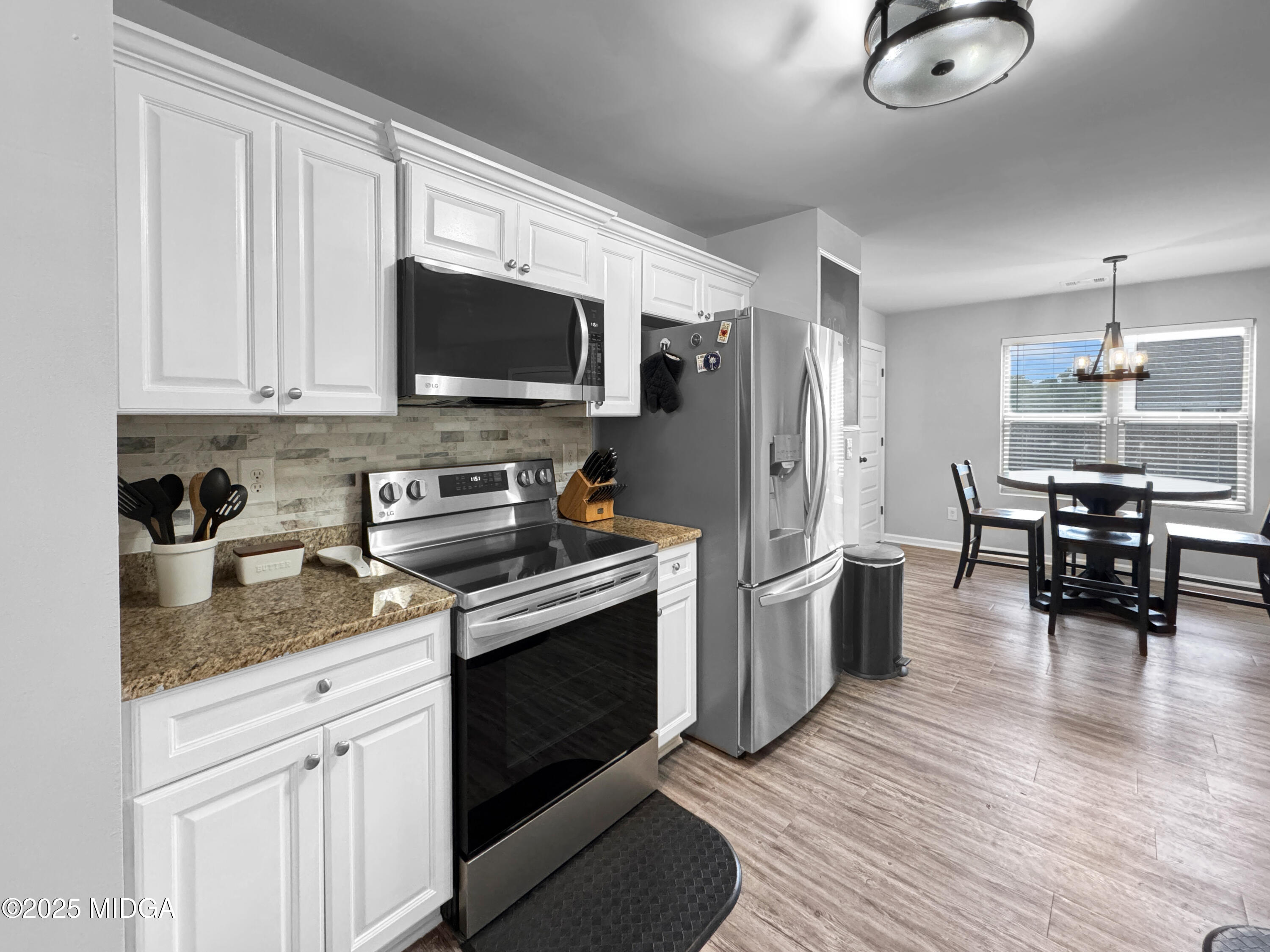 837 Weldon Road Forsyth, GA 31029 - Photo 4 of 24 a kitchen with stainless steel appliances granite countertop a stove top oven a sink dishwasher a dining table and chairs with wooden floor