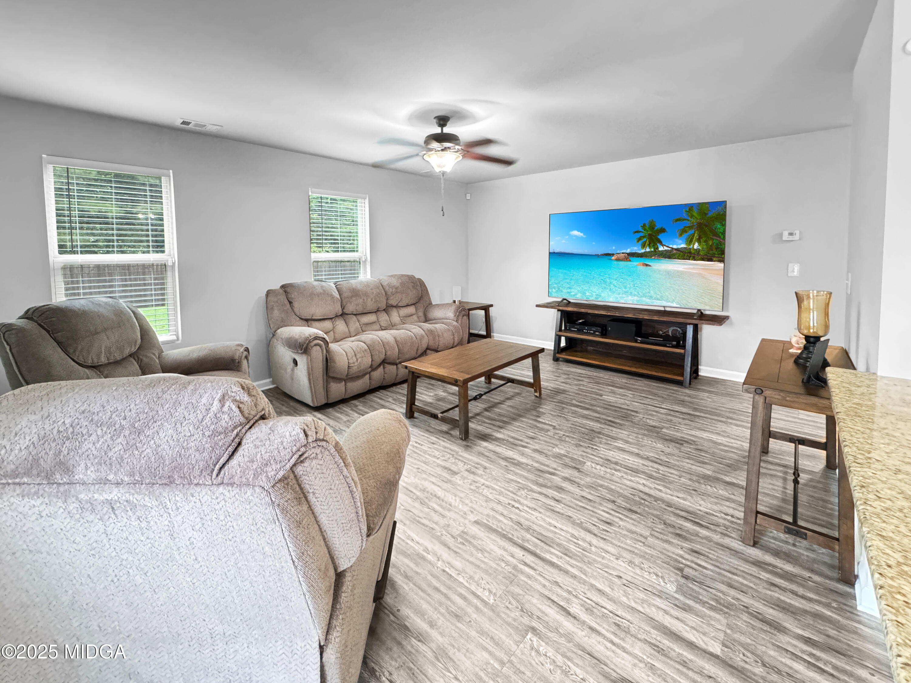 837 Weldon Road Forsyth, GA 31029 - Photo 8 of 24 a living room with furniture a wooden floor and a flat screen tv