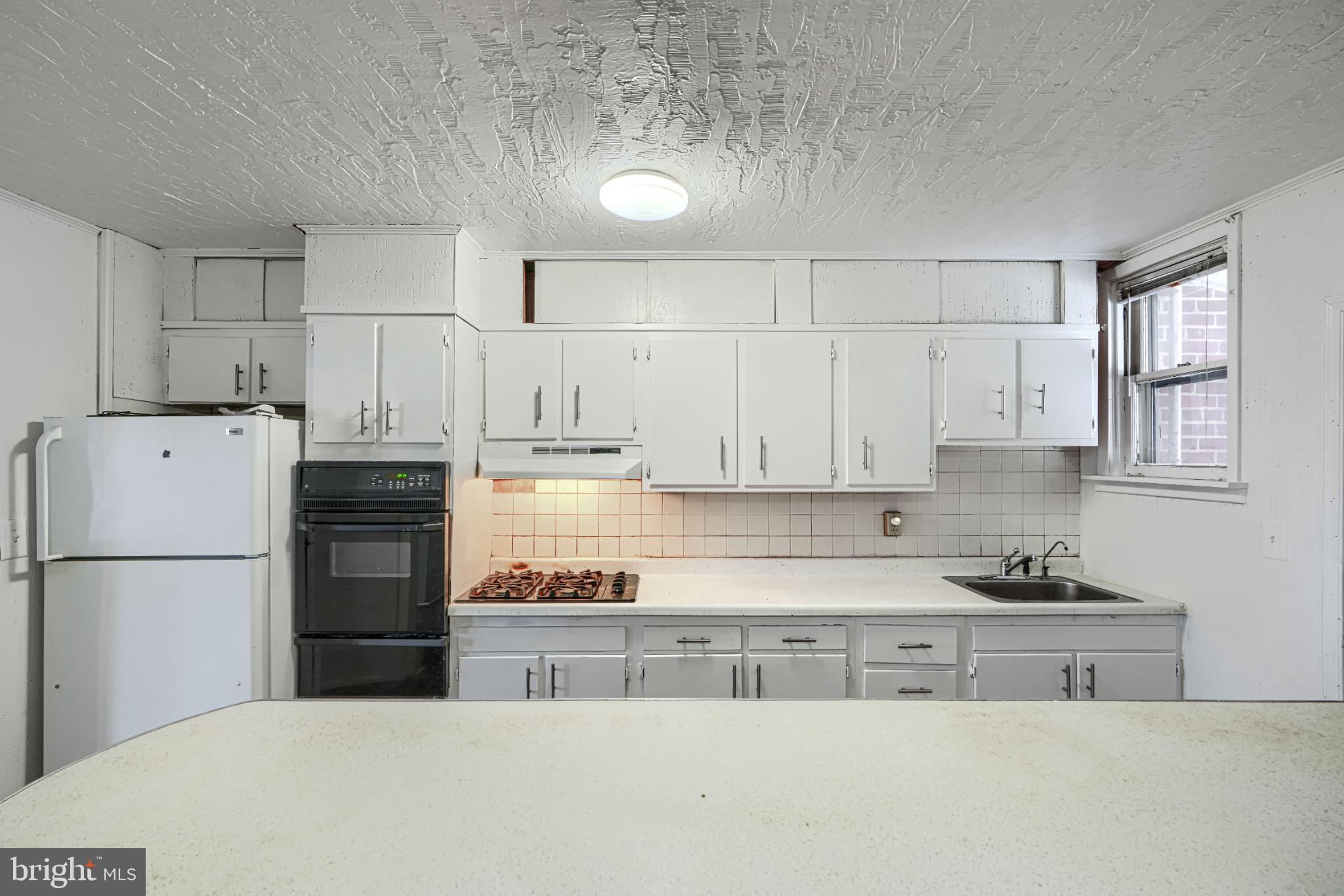 1302 Edison Highway Baltimore, MD 21213 - Photo 9 of 27 a kitchen with refrigerator a stove a sink and white cabinets