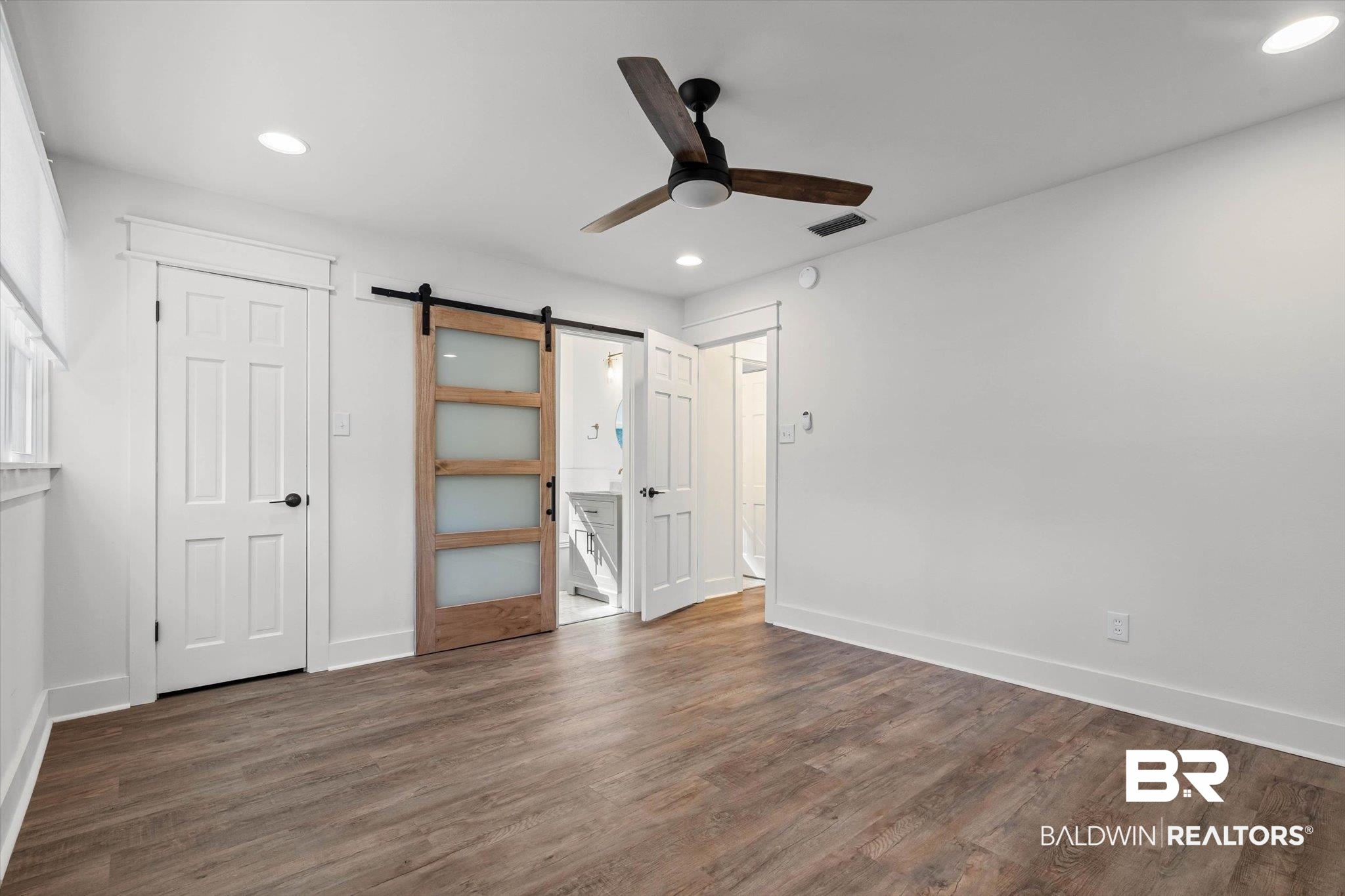 3933 Radnor Avenue Mobile, AL 36608 - Photo 19 of 36 Primary Bedroom, barn door, dark wood-style flooring, ceiling fan, En-suite bathroom, recessed lighting. Tip: For more space, the potential addition of a door on the back wall would connect to the front bedroom with walk-in closet! Use room as - options!