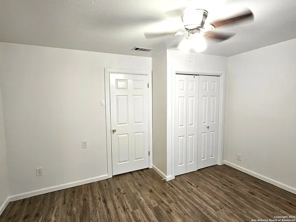a view of an empty room with window and a chandelier fan
