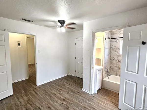 a view of empty room with wooden floor and fan