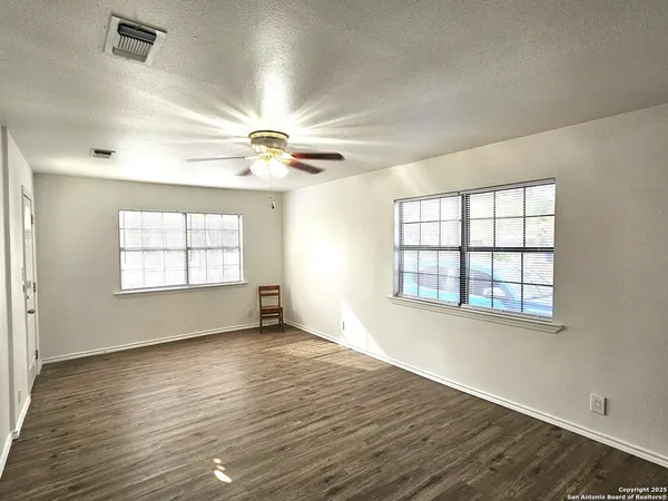 an empty room with wooden floor and windows