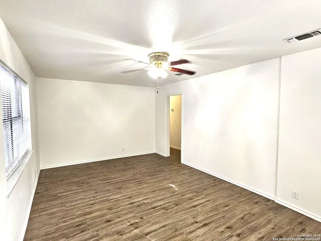 a view of an empty room with window and a ceiling fan