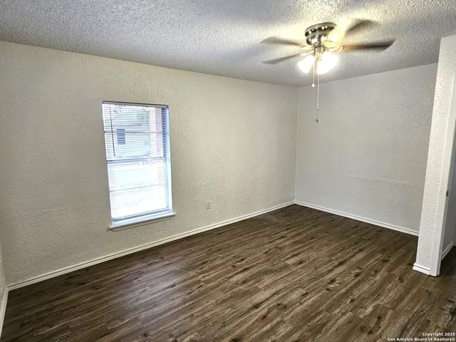 an empty room with wooden floor chandelier fan and window