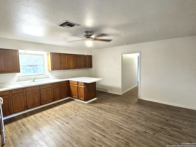 a large kitchen with a large counter top a sink stainless steel appliances and cabinets