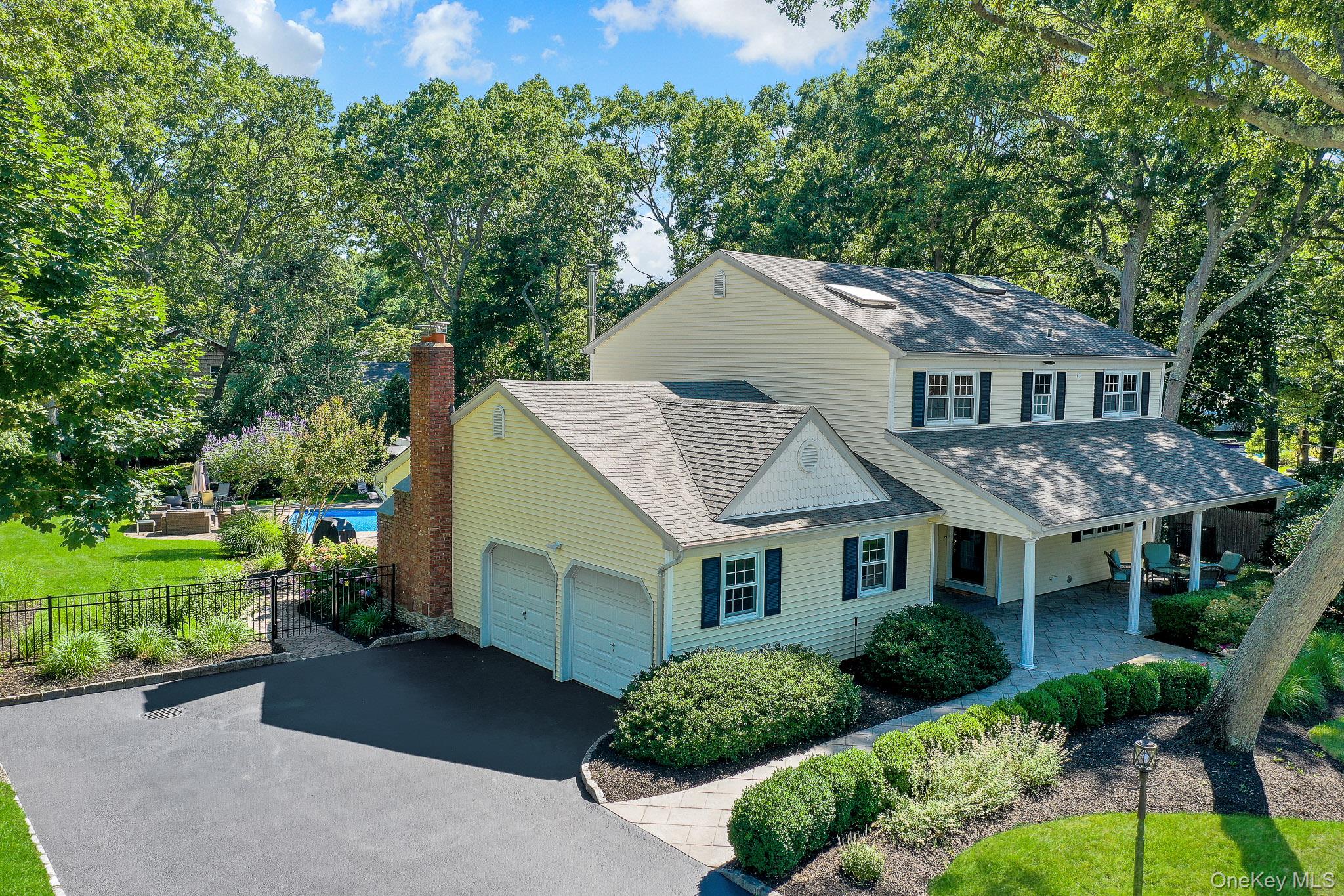 24 Fox Road East Setauket, NY 11733 - Photo 3 of 48 Two-story residence featuring light yellow siding, dark shutters, and a covered front patio with a stone paver surface
