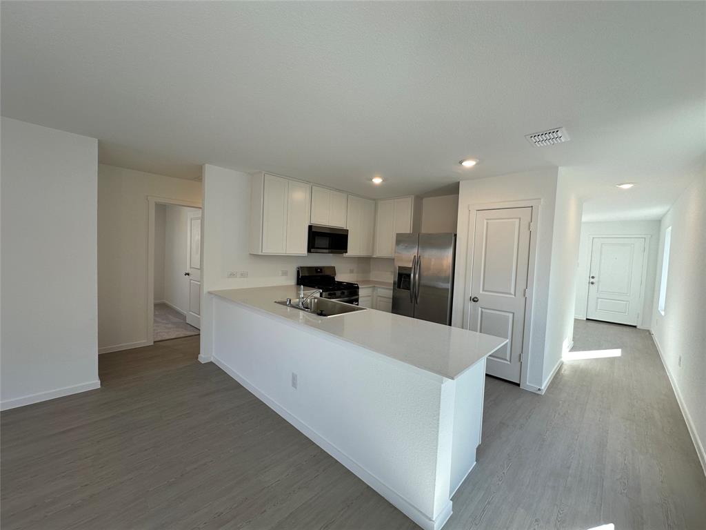 1617 Elliott Road Howe, TX 75459 - Photo 3 of 14 a large white kitchen with a refrigerator a sink and a stove top oven with wooden floor
