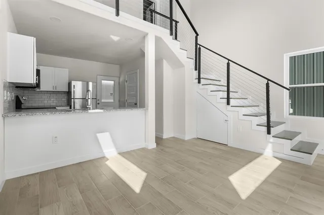 a view of a livingroom with wooden floor and stairs