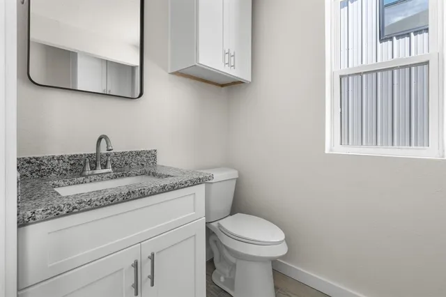 a bathroom with a granite countertop toilet sink and mirror