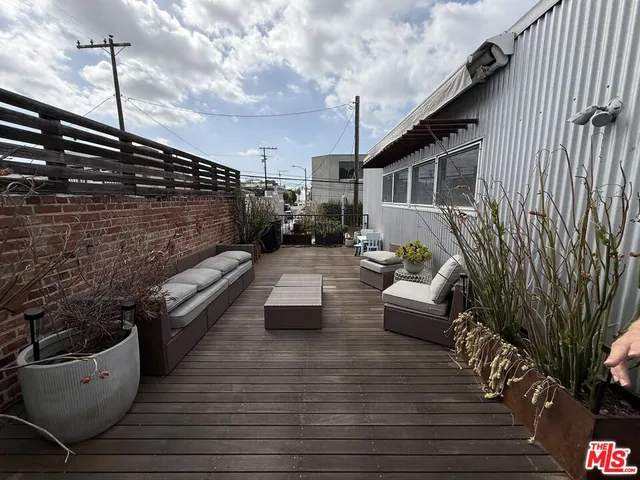 a view of a patio with couches table and chairs with wooden floor and fence
