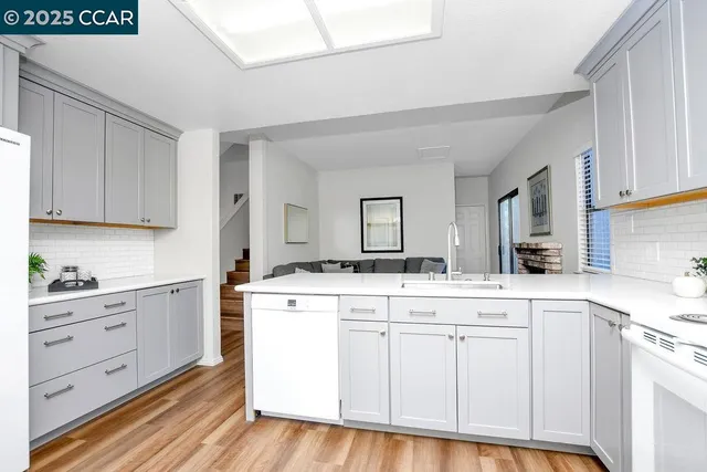 a kitchen with white cabinets and sink
