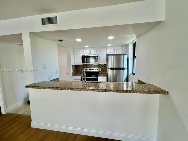 a large kitchen with granite countertop a sink and a refrigerator