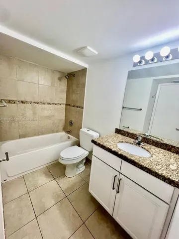 a bathroom with a granite countertop sink a toilet a mirror and bathtub