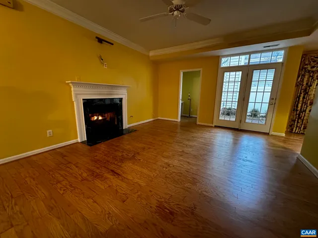an empty room with wooden floor fireplace and windows