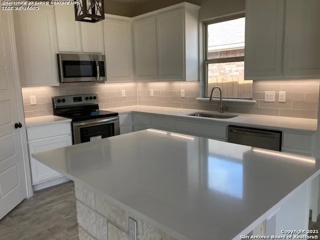 a kitchen with stainless steel appliances a stove a sink a microwave a refrigerator and cabinets