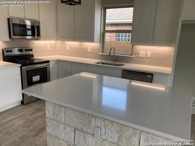 a kitchen with kitchen island granite countertop a sink cabinets and stainless steel appliances