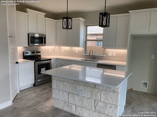 a kitchen with kitchen island granite countertop a sink stainless steel appliances and white cabinets