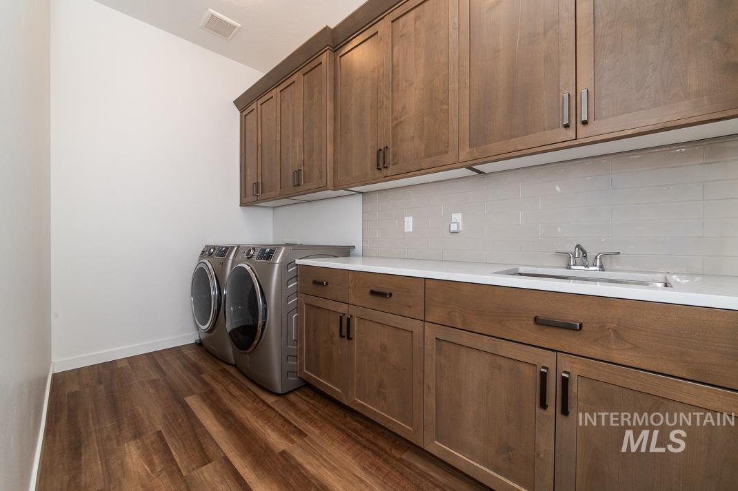 5610 Sparky Avenue Caldwell, ID 83607 - Photo 13 of 14 Laundry area with separate washer and dryer, dark wood-style floors, and cabinet space