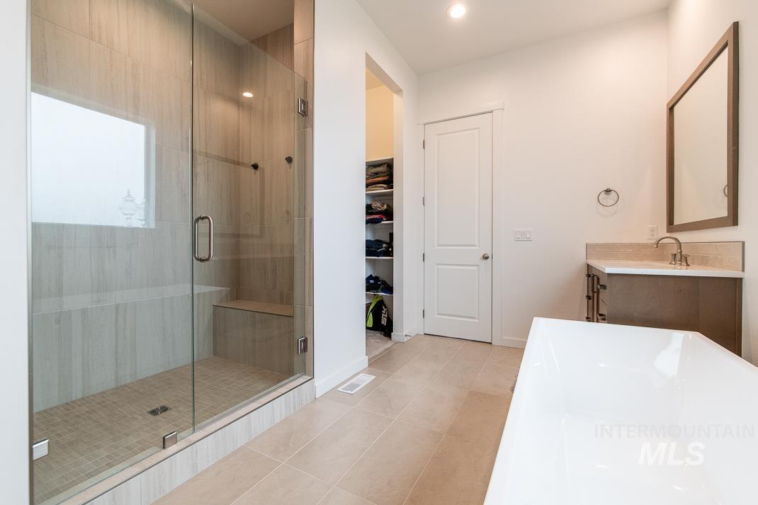 5610 Sparky Avenue Caldwell, ID 83607 - Photo 14 of 27 Full bath with vanity, a stall shower, a soaking tub, a walk in closet, and light tile patterned flooring
