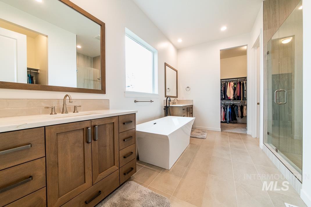 5610 Sparky Avenue Caldwell, ID 83607 - Photo 10 of 14 Full bathroom with a spacious closet, two vanities, a freestanding bath, a shower stall, and light tile patterned flooring