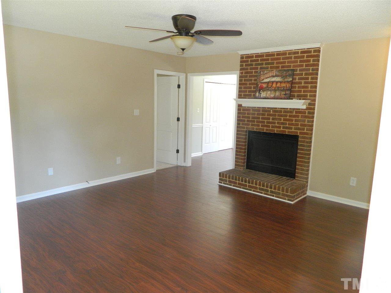 3624 Castlegate Drive Raleigh, NC 27616 - Photo 3 of 15 an empty room with wooden floor fireplace and windows