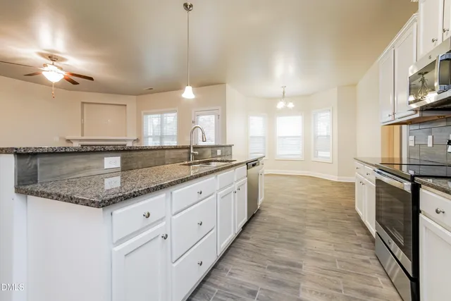 a large kitchen with granite countertop a large counter top space appliances and a sink