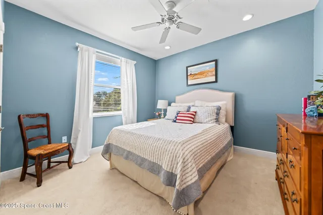 a bedroom with a bed a chair and a dresser next to a window