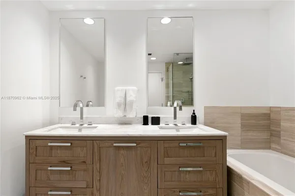 a bathroom with a sink vanity tub and a mirror