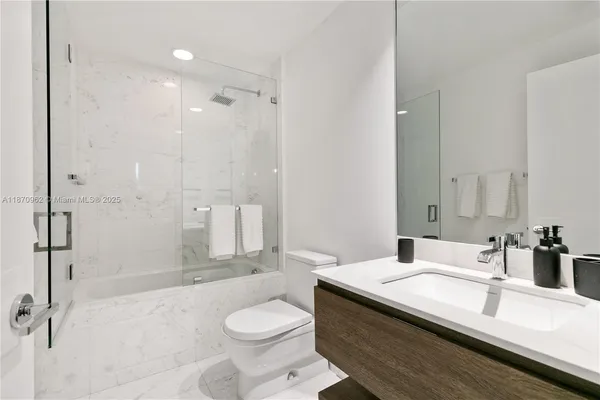a bathroom with a granite countertop sink a toilet a mirror and shower