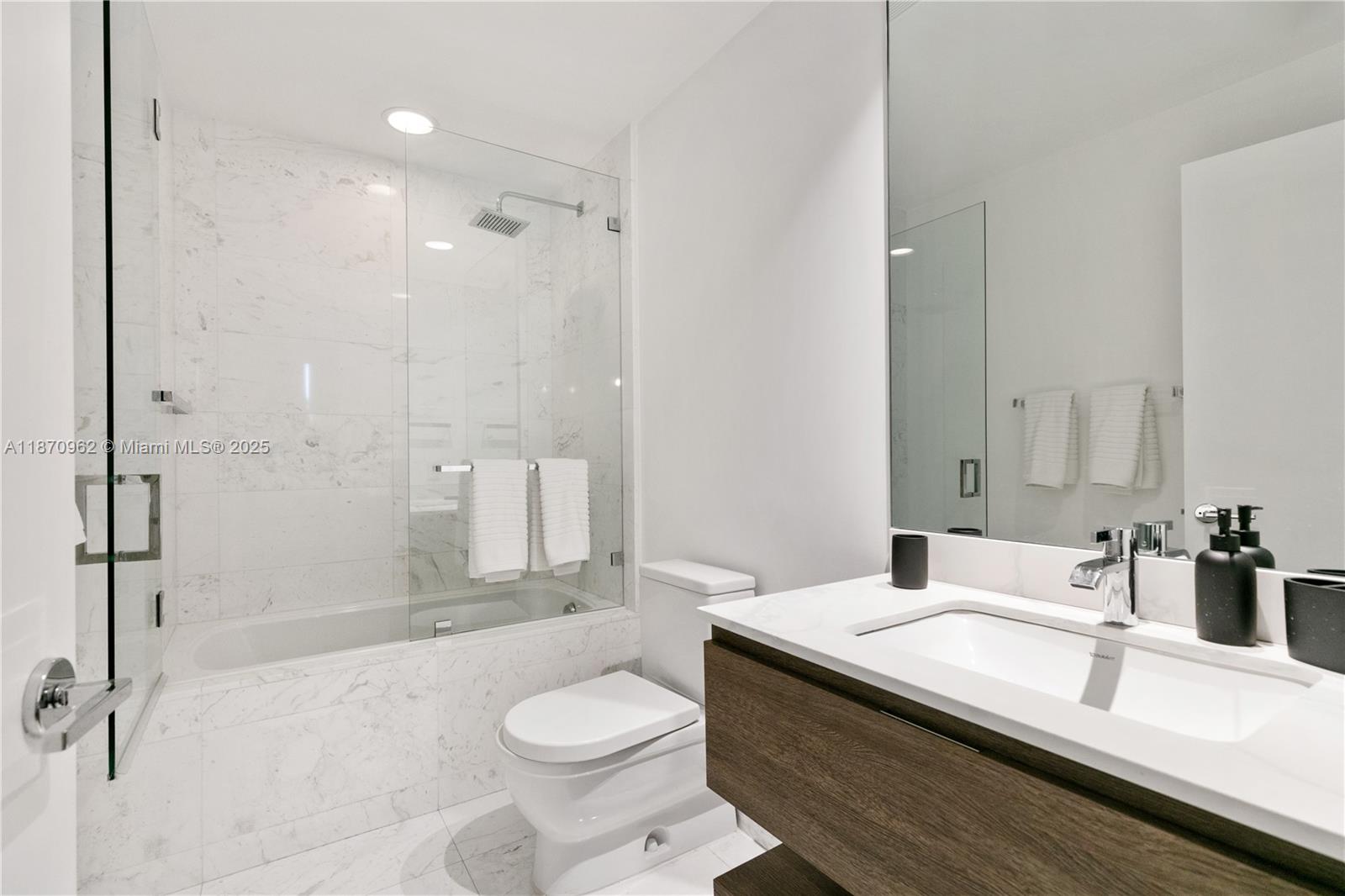 360 Ocean Drive, Unit 305S Key Biscayne, FL 33149 - Photo 26 of 27 a bathroom with a granite countertop sink a toilet a mirror and shower