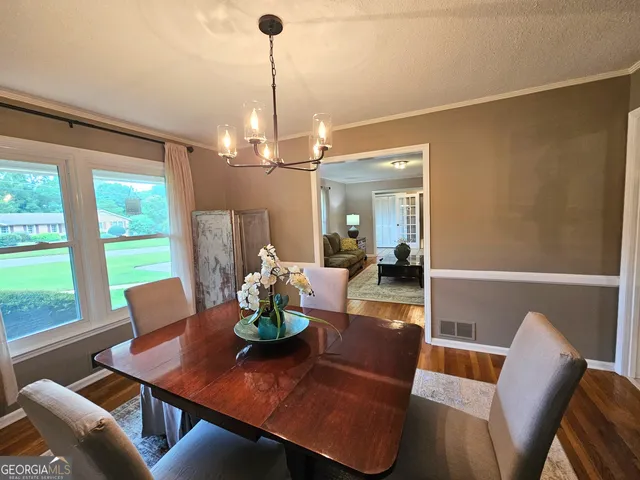 a view of a dining room and livingroom with furniture wooden floor a chandelier