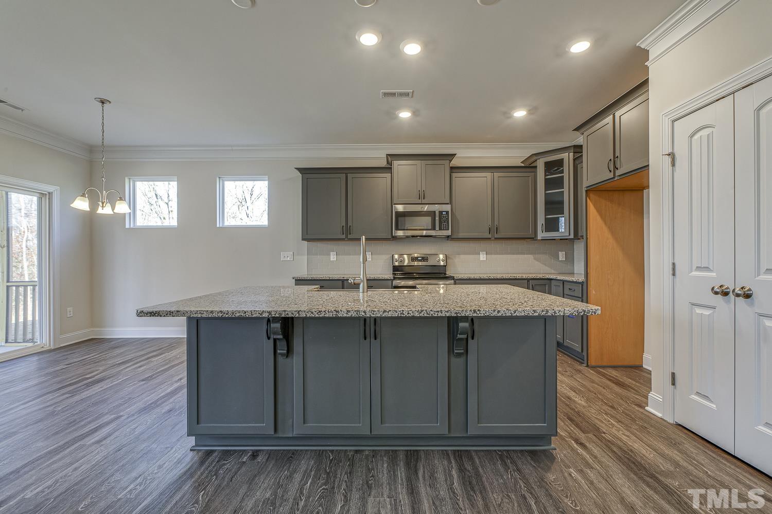 435 Cliffview Drive Garner, NC 27529 - Photo 15 of 45 a kitchen with kitchen island granite countertop wooden floors white cabinets and stainless steel appliances
