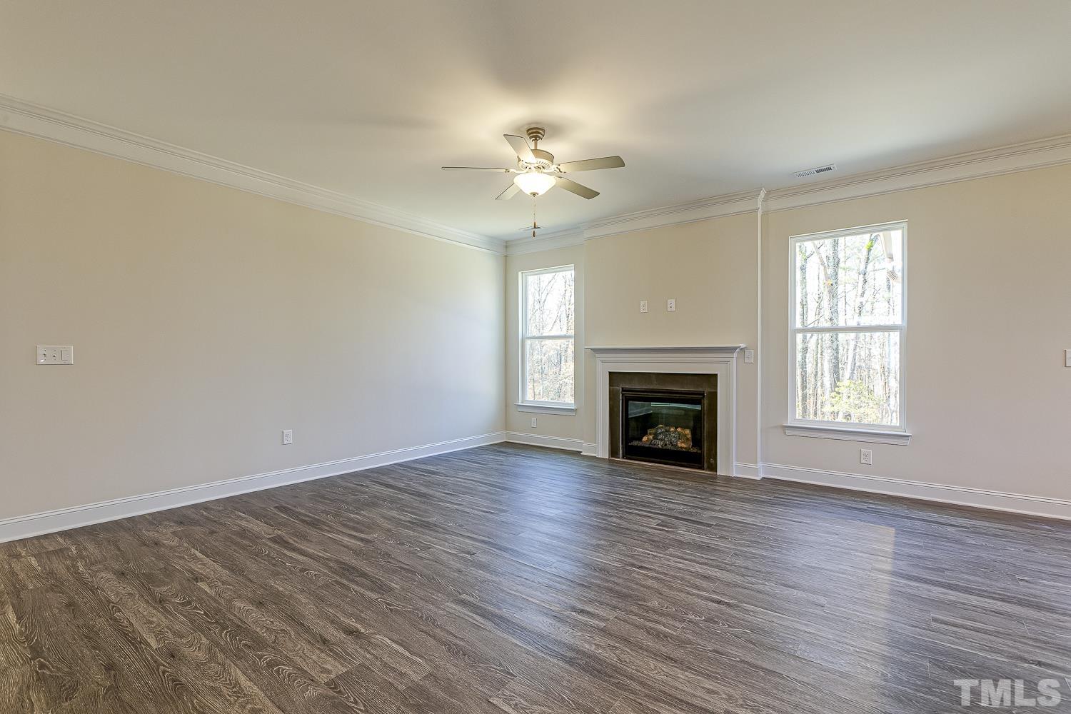 435 Cliffview Drive Garner, NC 27529 - Photo 19 of 45 an empty room with windows a fireplace and a chandelier fan