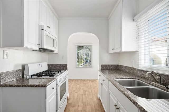 a kitchen with granite countertop a sink stove and cabinets