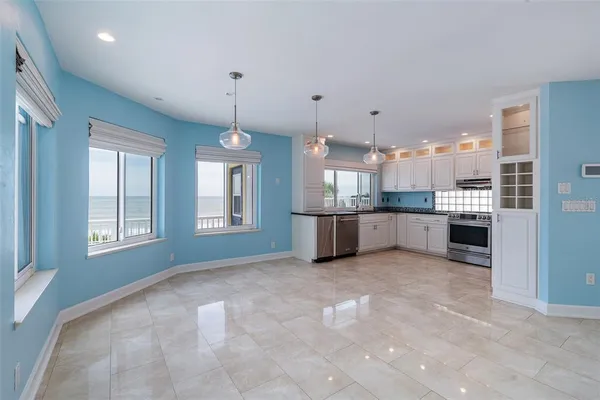 a view of an empty room with a window and a kitchen