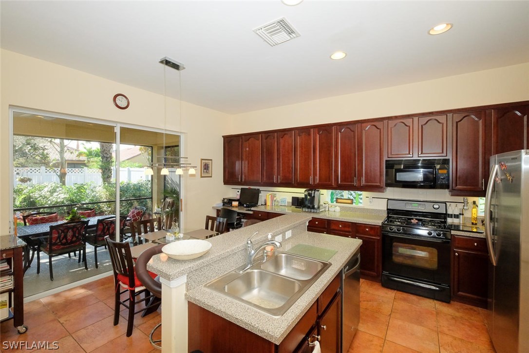 12882 Timber Ridge Drive Fort Myers, FL 33913 - Photo 8 of 25 a kitchen with a stove a sink a microwave a dining table and chairs