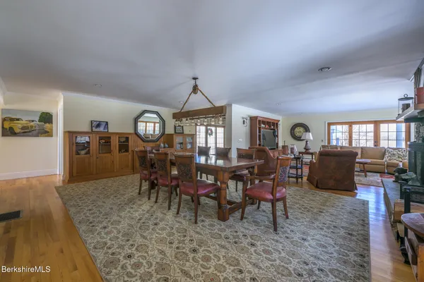 a view of a dining room and livingroom with furniture a rug a rug and a clock