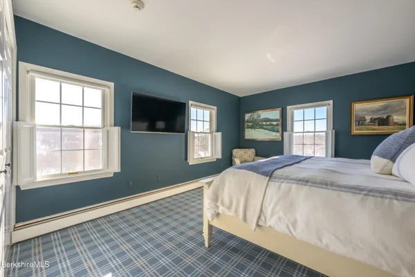 a spacious bedroom with a bed and dresser with wooden floor