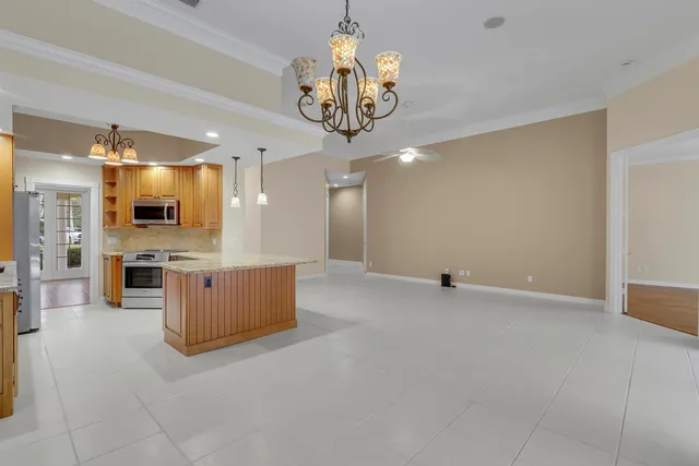 a view of an empty room and kitchen with stainless steel appliances