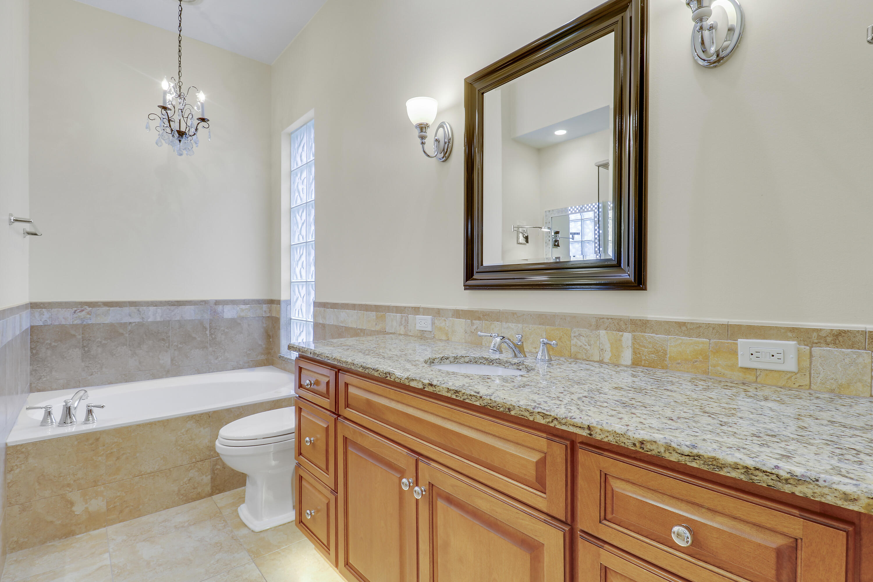 8657 Southeast Nicolete Lane Hobe Sound, FL 33455 - Photo 28 of 50 a bathroom with a granite countertop sink mirror vanity bathtub and a toilet