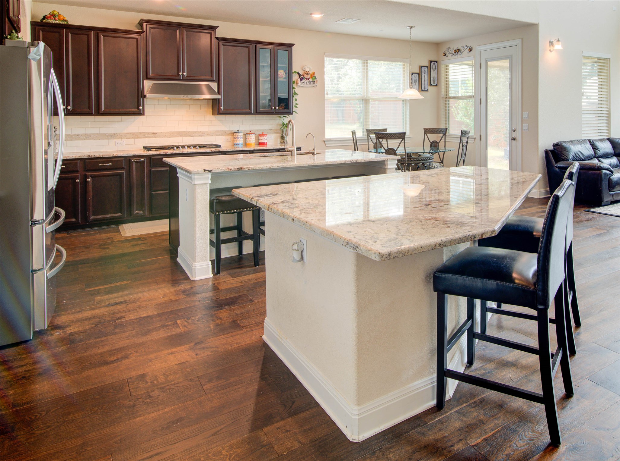 15621 Cabrillo Way Austin, TX 78738 - Photo 8 of 21 a kitchen with stainless steel appliances granite countertop a stove top oven a sink a dining table and chairs with wooden floor