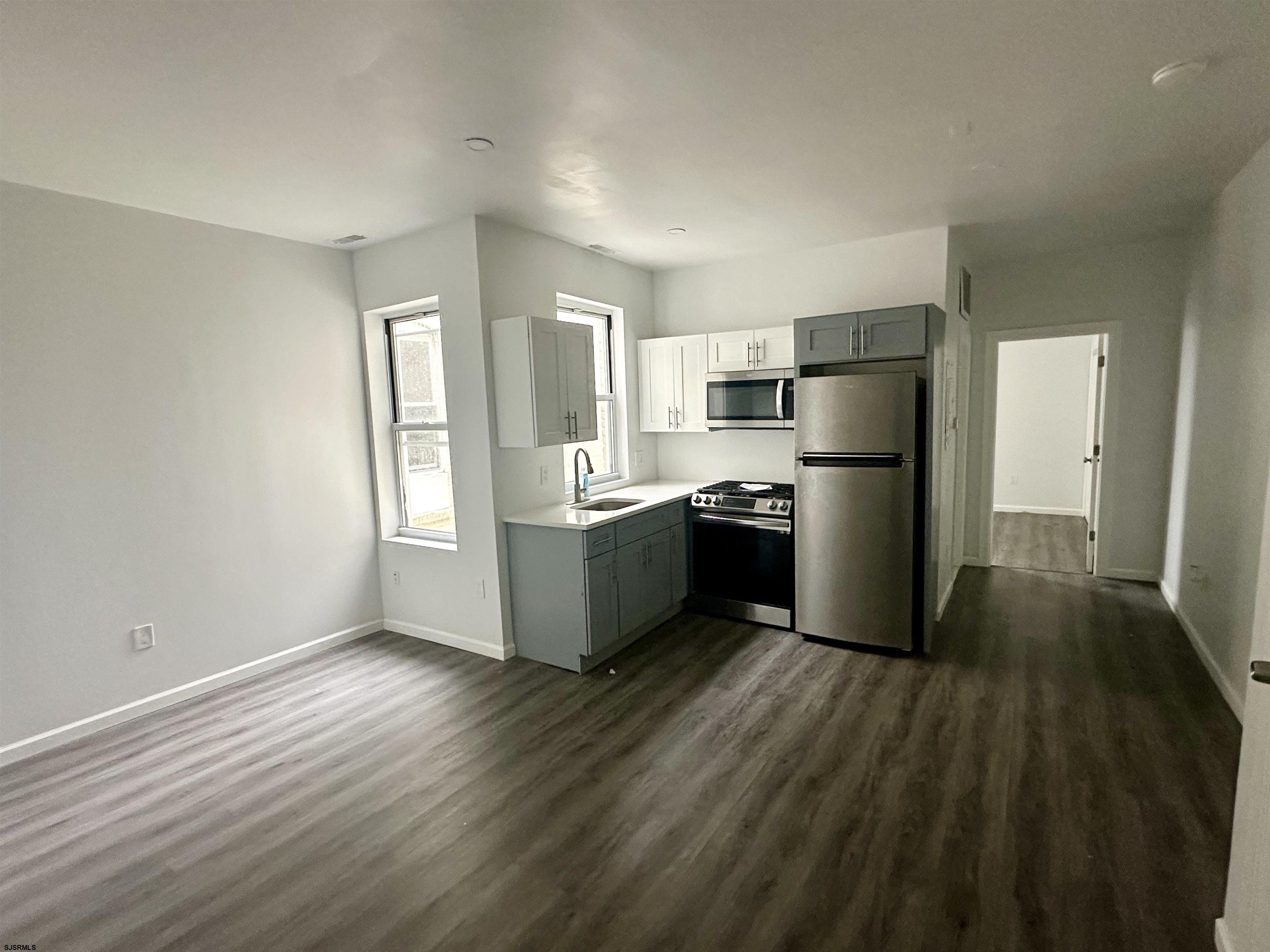 225 Atlantic Avenue, Unit A6 Atlantic City, NJ 08401 - Photo 22 of 29 a kitchen with a refrigerator a sink and dishwasher with wooden floor