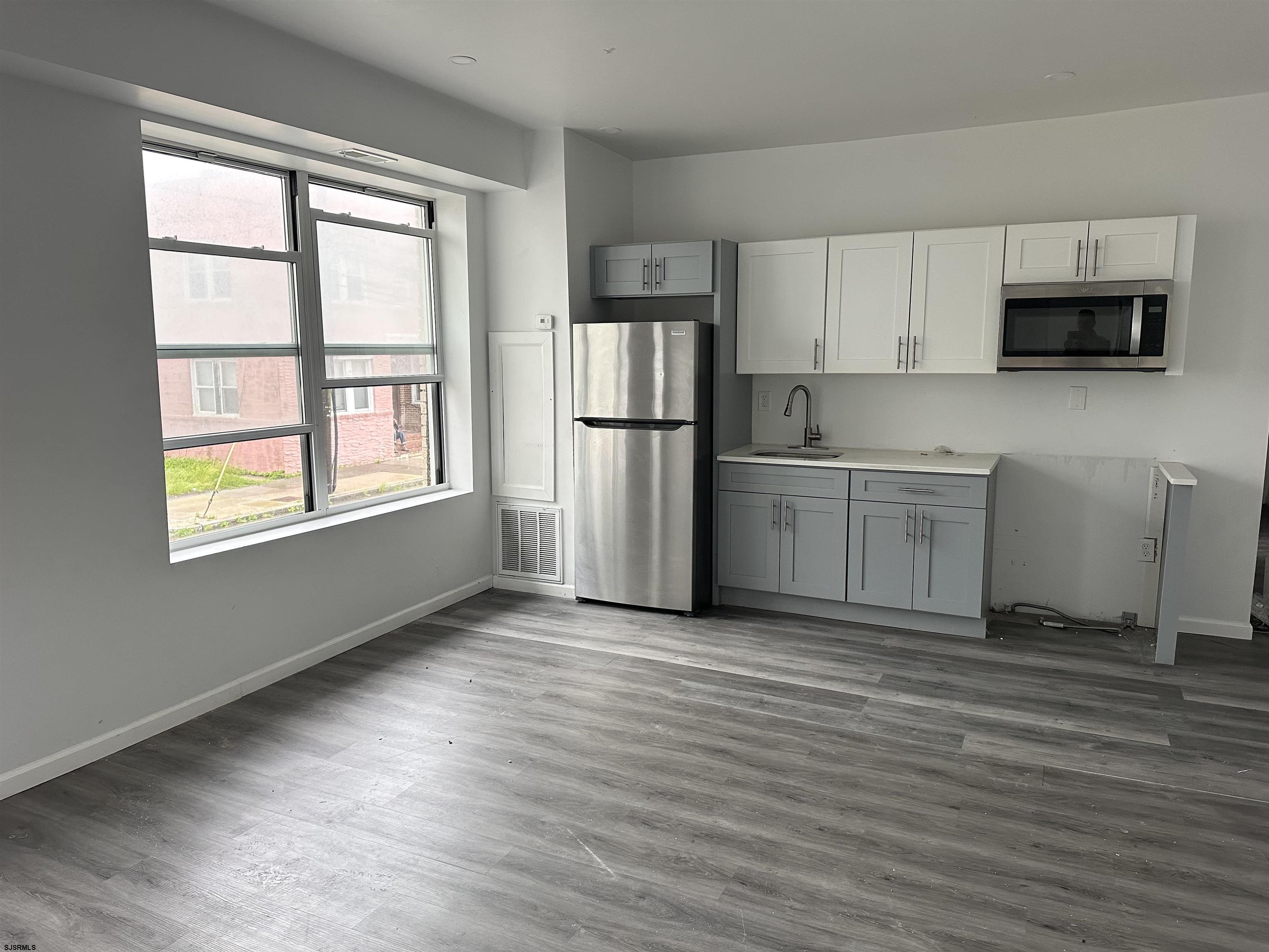 225 Atlantic Avenue, Unit A6 Atlantic City, NJ 08401 - Photo 6 of 29 a view of kitchen with stainless steel appliances granite countertop a stove top oven a refrigerator and white cabinets with wooden floor
