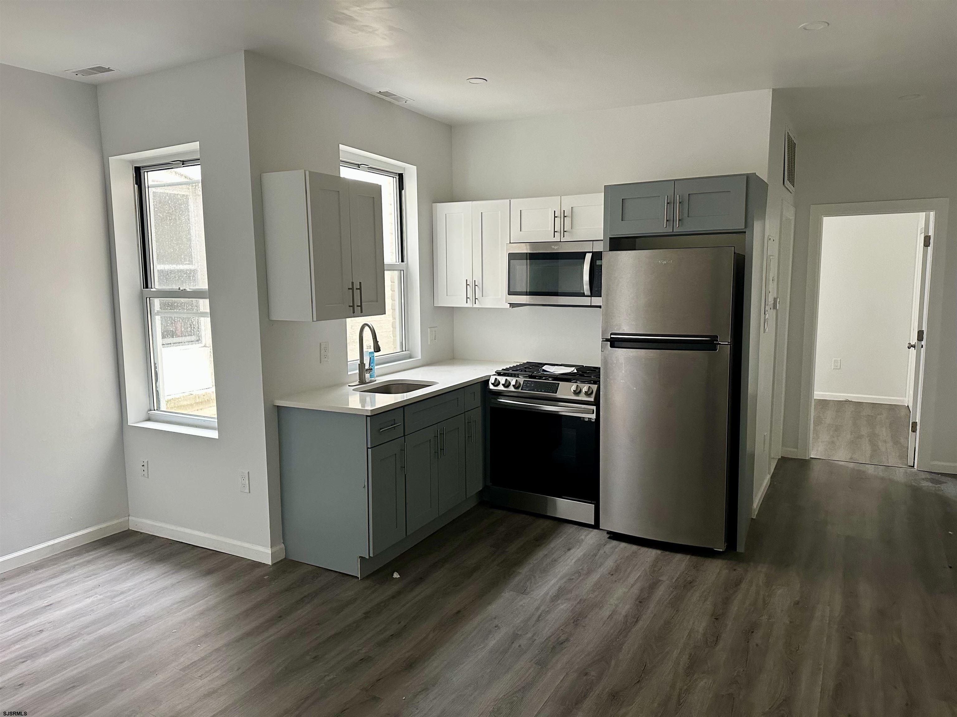 225 Atlantic Avenue, Unit A6 Atlantic City, NJ 08401 - Photo 7 of 29 a kitchen with a refrigerator a stove top oven and wooden floor