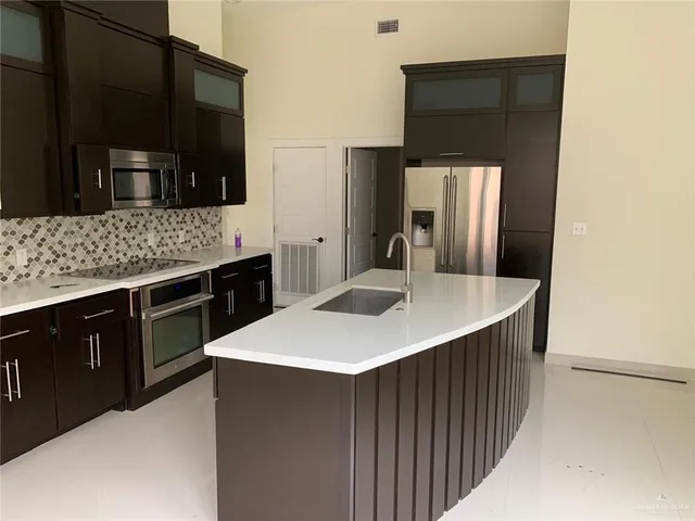 a kitchen with stainless steel appliances a kitchen island a stove a sink and a refrigerator