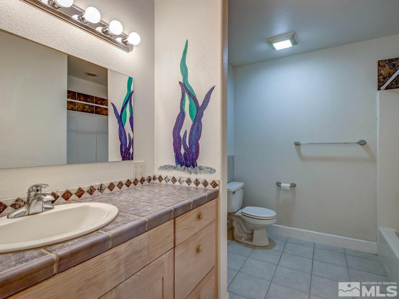 20575 Cooke Drive Reno, NV 89521 - Photo 12 of 25 a bathroom with a granite countertop sink a large mirror and a toilet