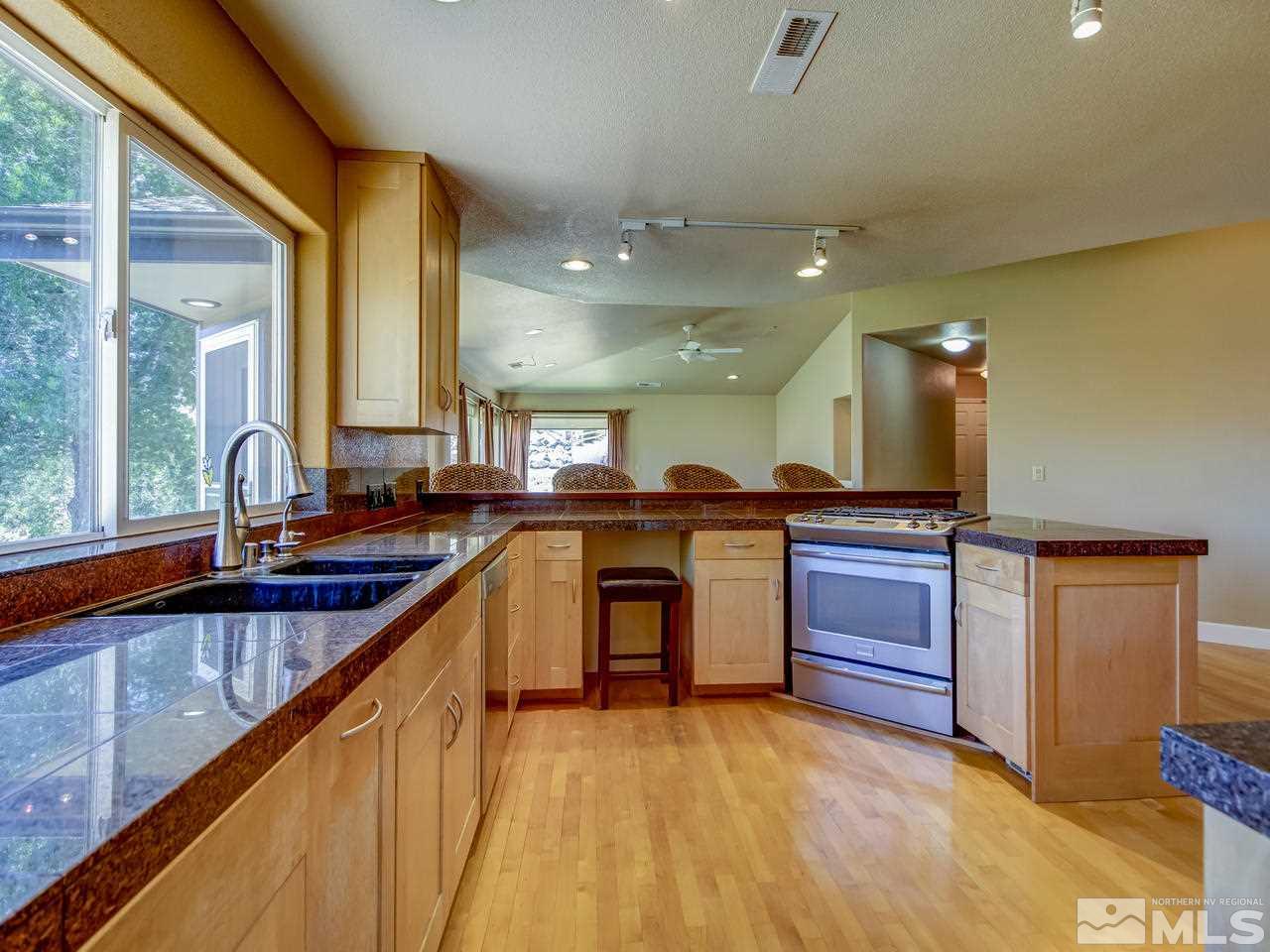 20575 Cooke Drive Reno, NV 89521 - Photo 5 of 25 a large kitchen with kitchen island a large counter space a sink a counter space and stainless steel appliances