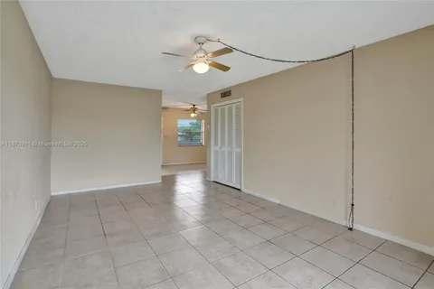 a view of an empty room and chandelier fan