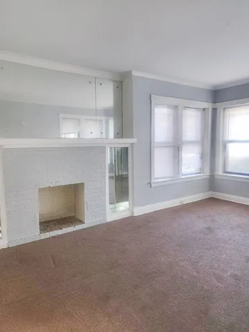 a view of an empty room with a window and fireplace